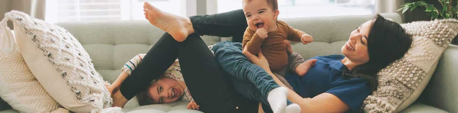 a-mother-and-her-two-children-laughing-and-sitting-on-the-couch-at-home_t20_XxloBl