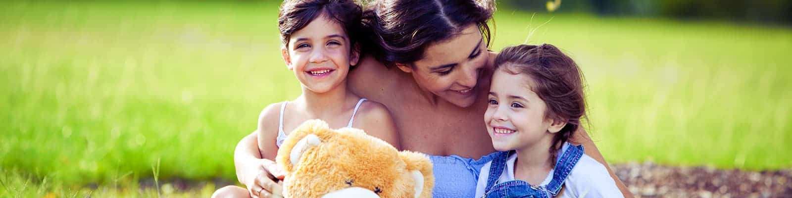 Young mother and two daughters playing in grass